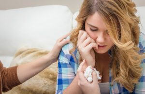Hands of mother consoling sad teen daughter crying