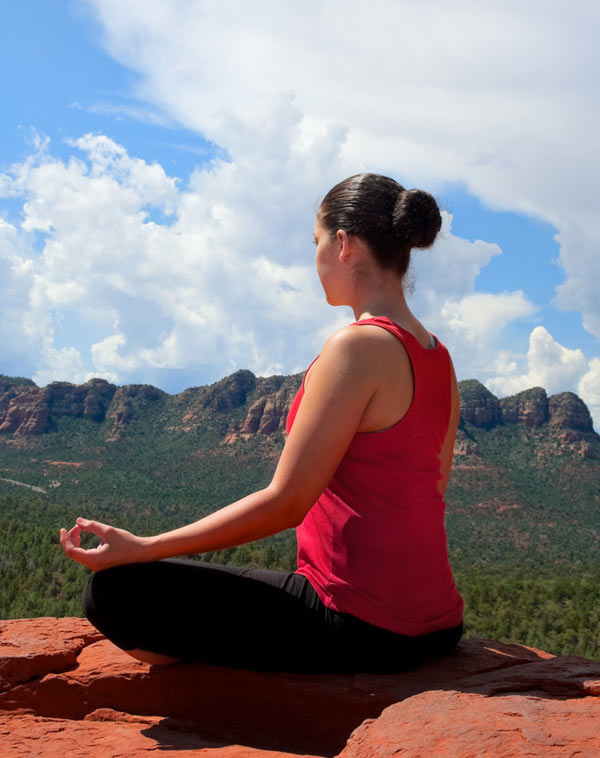 Woman meditating on Sedona red rocks during an individual healing retreat
