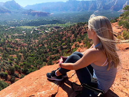 Woman sitting peacefully on a Sedona red rock overlook during an individual healing retreat